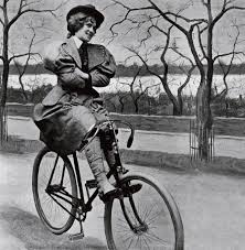 Black and white photo of proper woman on an old bicycle